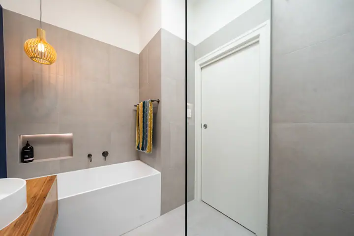 Bath beside a tiled shower with a recessed niche