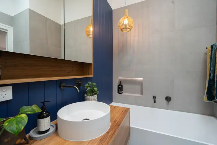 Timber vanity with a mirrored cabinet next to a built-in bath