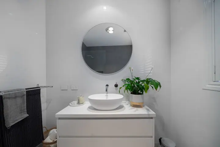 White floating vanity with a round mirror and vessel basin