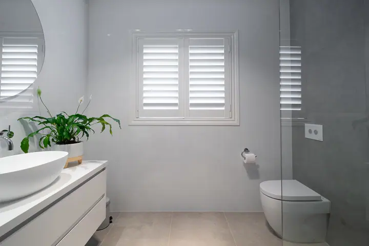 White vanity, wall-hung toilet and plantation shutters